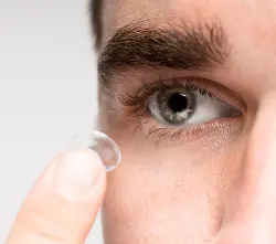 Man inserting contact lens into eye – Buy contact lenses online